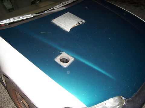 1994 Ford Probe - A car hood is modified with two metal vents, one square and one rectangular, painted teal and white.