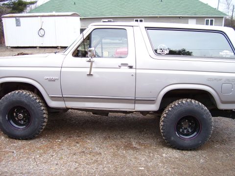 1984 Ford Bronco - Side profile of a silver 1984 Ford Bronco, equipped with large off-road tires.
