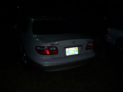 1994 Ford Probe - A white sedan is parked at night, showing its rear end and license plate.