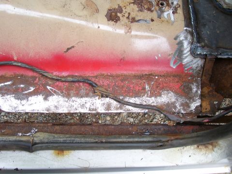 1984 Ford Bronco - This photo shows significant rust and damage to a vehicle's floor pan, with exposed wiring visible.