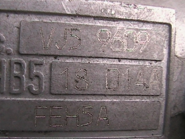 Close-up of a metal plate with stamped numbers and letters: VJ5 9609, HB5 18 014A, FEH5A. Supermotors.net logo at bottom right