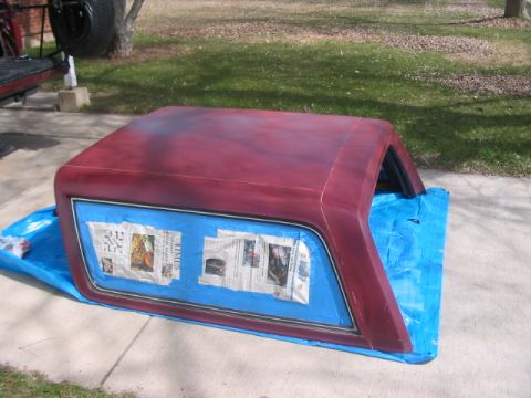 1991 Ford Bronco - A vehicle hardtop is covered in a blue tarp and newspaper, likely being prepped for painting.