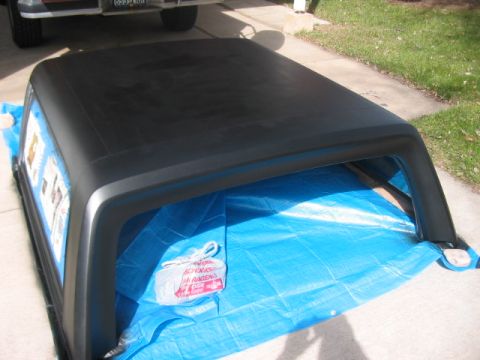 1991 Ford Bronco - The black hardtop for a 1991 Ford Bronco is shown on a blue tarp, with another vehicle visible in the background.