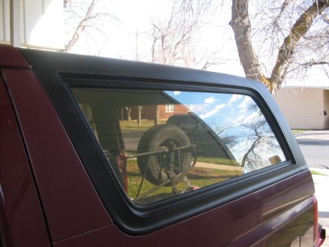 1991 Ford Bronco - The side profile of a red 1991 Ford Bronco is visible, with a spare tire mounted inside the cargo area.