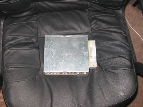 1991 Ford Bronco - Ford electronic control unit shown on a black leather seat. The part number is visible on the side label.