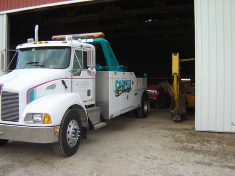 1992 Ford Bronco - Tow truck and construction equipment are parked inside a garage structure.