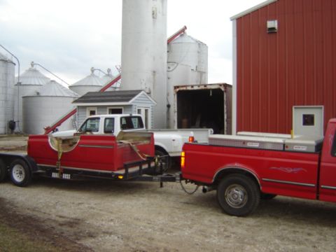 1992 Ford Bronco - A red pickup truck tows a trailer carrying a custom red truck bed, with another pickup nearby.