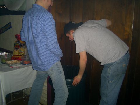 1985 Ford Bronco - Two men are near a trash can in a room with wood-paneled walls.