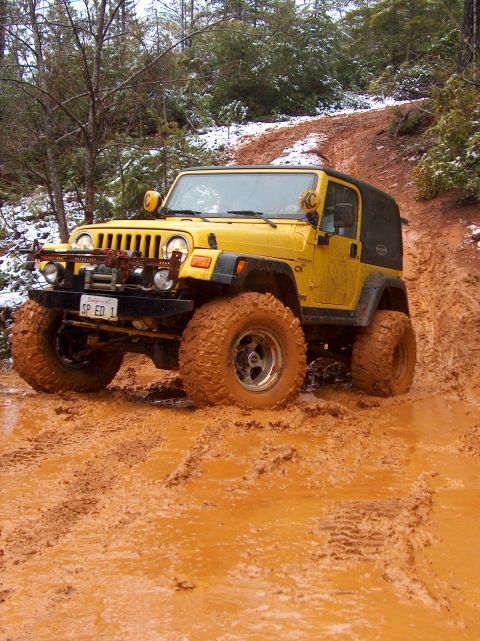 1993 Ford Bronco - This Jeep is navigating a challenging muddy terrain with some snow visible in the background.