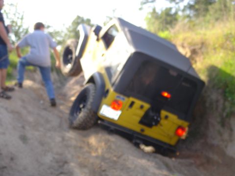 2002 Jeep Wrangler - A yellow 2002 Jeep Wrangler navigates a steep dirt incline with a person watching.