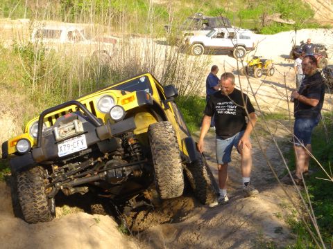 2002 Jeep Wrangler - Yellow Jeep Wrangler navigating an off-road trail with other vehicles present.