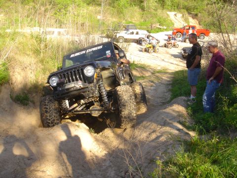 2002 Jeep Wrangler - Several off-road vehicles and people are gathered on a dirt trail during an outdoor event.