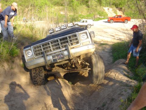 2002 Jeep Wrangler - A lifted truck navigates a challenging off-road trail with spectators watching.
