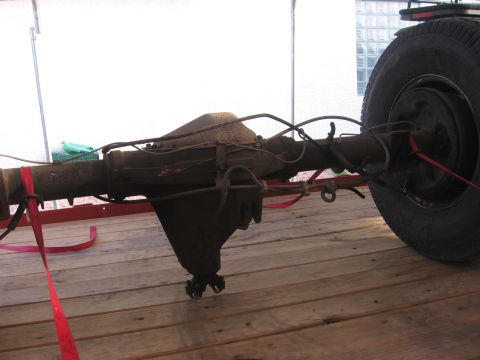 1990 Ford Bronco - A rear axle assembly, likely from a truck or SUV, is shown secured with red straps on a wooden surface.