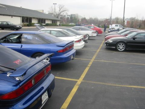 1993 Ford Probe - A line of cars, including a blue 1993 Ford Probe, parked in a lot.