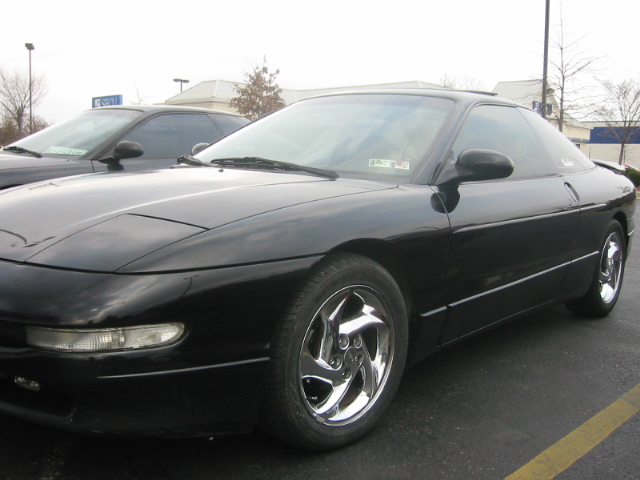 Black Ford Probe with chrome three-spoke wheels parked in a lot, front three-quarter view