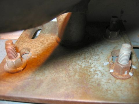 1985 Ford LTD Crown Victoria - A close-up view of a corroded metal bracket with exposed bolts, suggesting a part of a vehicle's undercarriage.