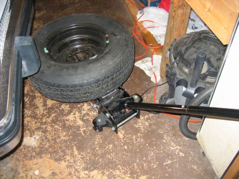1985 Ford LTD Crown Victoria - Spare tire and car jack on a workshop floor.