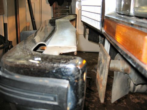 1985 Ford LTD Crown Victoria - A close-up view of a vehicle's front bumper and grille area, with an orange turn signal light visible.