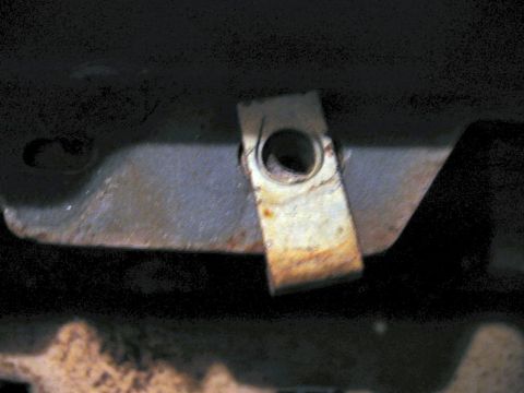 1985 Ford LTD Crown Victoria - A close-up view of a rusty metal clip on the underside of a vehicle.