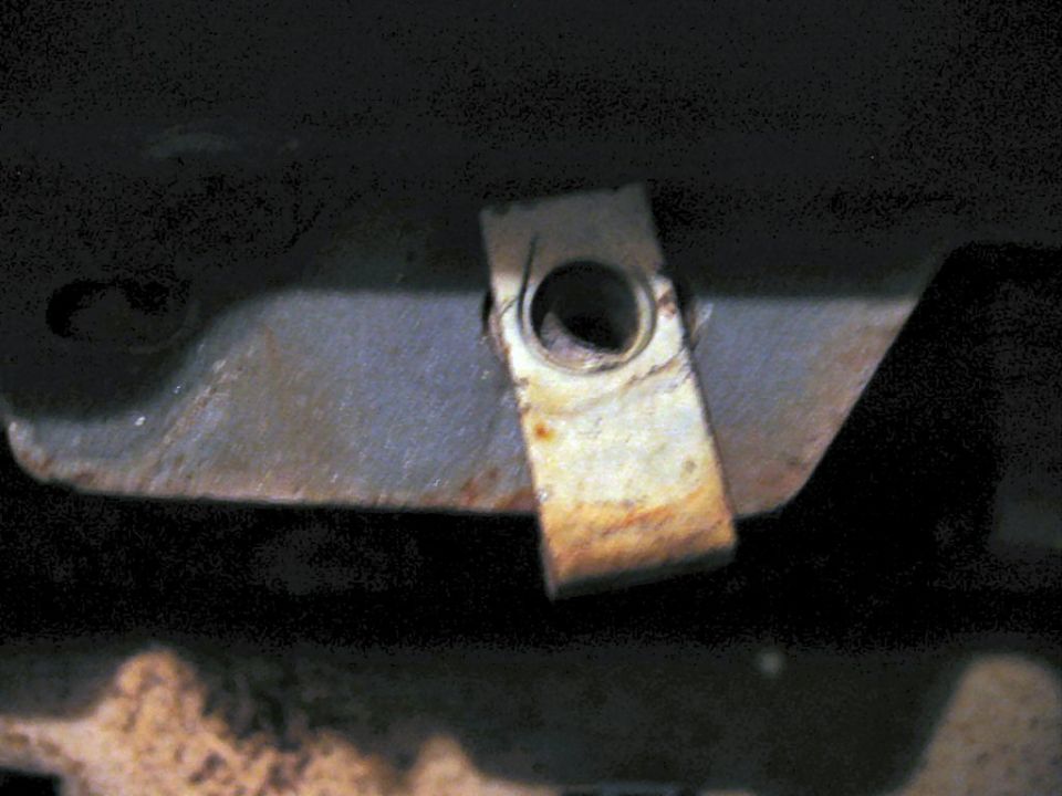 Rusty metal clip on car's undercarriage