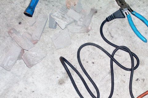 1991 Ford Bronco - Pieces of a broken exhaust pipe lie on the ground with tools nearby.