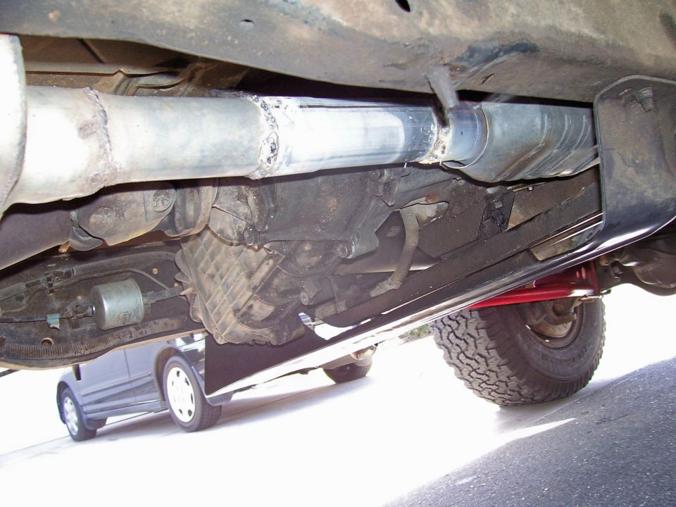 Newly welded aluminized exhaust pipe under a truck alongside transmission and transfer case