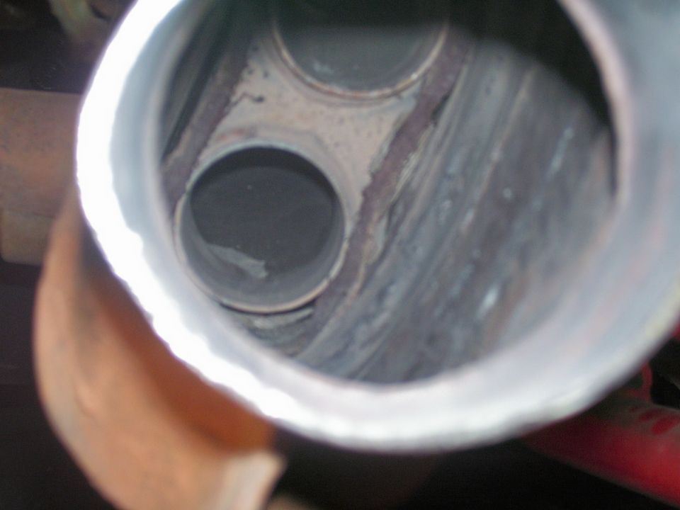 Looking into the open inlet of a gutted exhaust component with internals removed