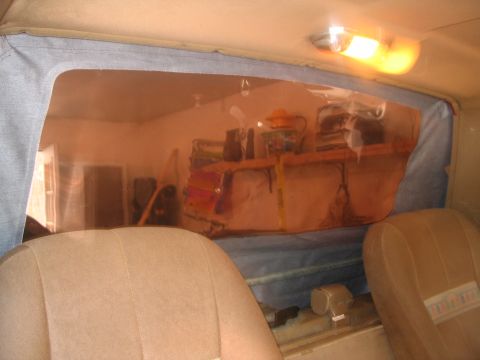 1989 Ford Bronco - View from inside a vehicle's cabin, looking through the rear window at a shelf with various items.