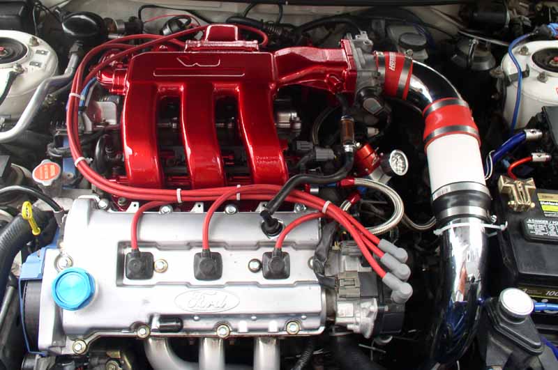 Engine bay with red intake manifold, Ford branding on engine block, and custom intake piping