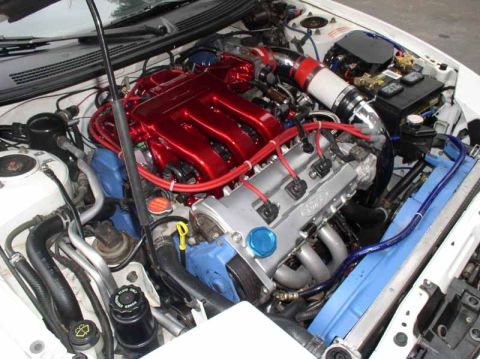 1996 Ford Probe - Close-up view of a modified engine bay, a prominent red intake manifold and a silver engine cover with Ford branding.