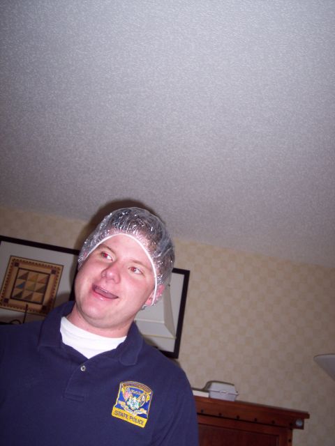 2001 Ford Crown Victoria - A man wearing a shower cap and a navy blue polo shirt with a state police patch is pictured.