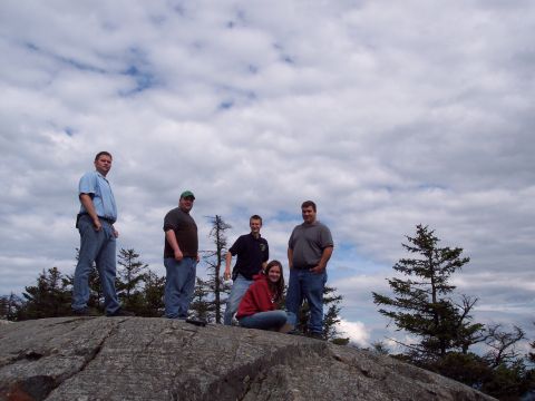 2001 Ford Crown Victoria - A group of five friends pose for a photo on a rocky outcrop, surrounded by trees under a cloudy sky.