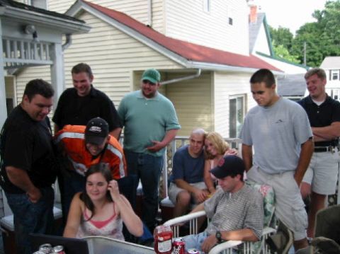 2001 Ford Crown Victoria - A group of friends and family are socializing on a porch, with some looking at a laptop.