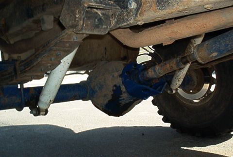 1986 Ford Bronco - Close-up of the rear axle, leaf springs, and shock absorbers on a vehicle's undercarriage.