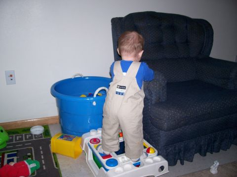 1981 Ford Bronco - A toddler stands on a toy, surrounded by other toys and furniture in a room.
