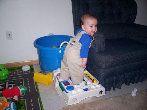 1981 Ford Bronco - Baby plays with toys in a room next to a blue bucket and a dark armchair.