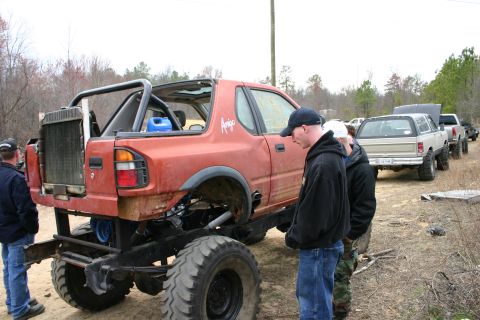 1989 Ford Bronco - Several modified trucks are lined up outdoors, with the foreground vehicle heavily customized.