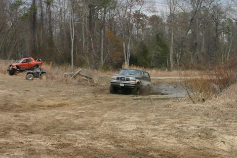 1989 Ford Bronco - A 1989 Ford Bronco navigates a muddy trail, with other off-road vehicles nearby.