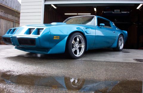 1979 Pontiac Trans Am - A bright blue 1979 Pontiac Trans Am with chrome wheels sits in front of an open garage door.