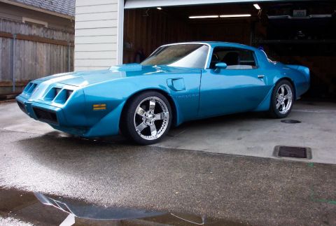 1979 Pontiac Trans Am - A bright blue Pontiac Firebird with custom wheels sits in a driveway.