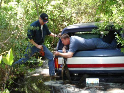 1989 Ford Bronco - Two men work to free a 1989 Ford Bronco stuck in the mud.