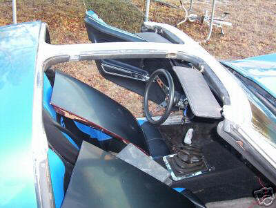 1993 Ford Bronco - The interior of a blue convertible sports car is shown with its doors open and parts disassembled.