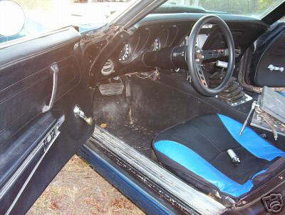 1993 Ford Bronco - The interior of a car is shown, black and blue seats and a racing steering wheel.