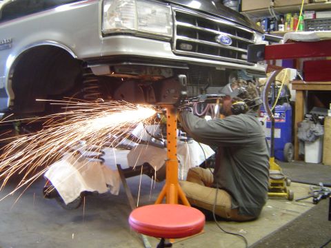 1989 Ford Bronco - A mechanic grinds the frame of a 1987 Ford F-Series truck during an axle installation.