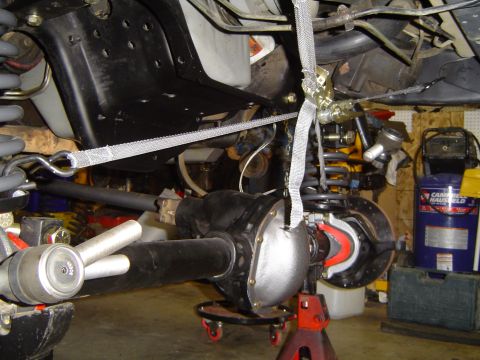 1989 Ford Bronco - Close-up view of a vehicle's axle assembly, supported by jack stands and straps during maintenance.