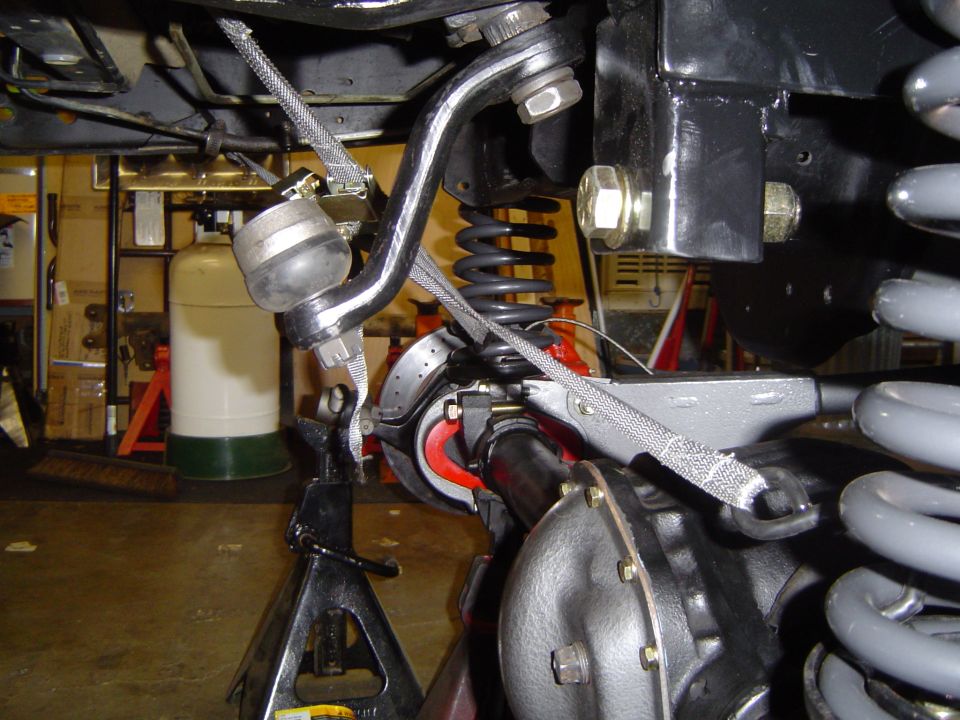Undercarriage shot of suspension showing coil spring, sway bar, and braided line in a garage