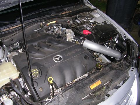 2004 Mazda 6 - The engine bay of a Mazda vehicle, the V6 engine cover and an aftermarket intake system.