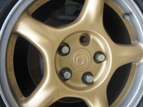 1995 Ford Probe - Gold 5-spoke wheel with a circular emblem and lug nuts, showing '16x7JJ' marking.