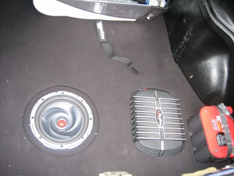 1995 Ford Probe - The trunk of a car contains a subwoofer, amplifier, and a red Optima battery.
